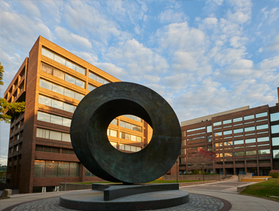 Photo of building on campus with a sculpture in front.